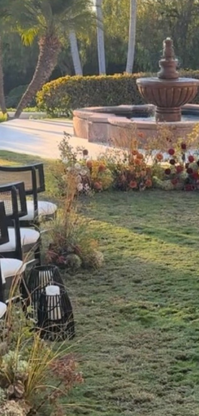 Autumn Romance ceremony space — estate lawn with black lanterns and a ground-level arrangement of burgundy and amber flowers beside a stone fountain — Lux Events by Michelle