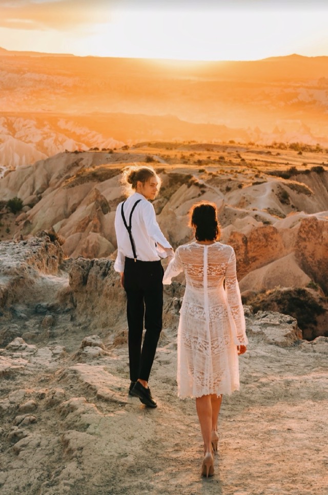 Bride and groom walk hand-in-hand along a golden desert ridge at sunset — Lux Events by Michelle