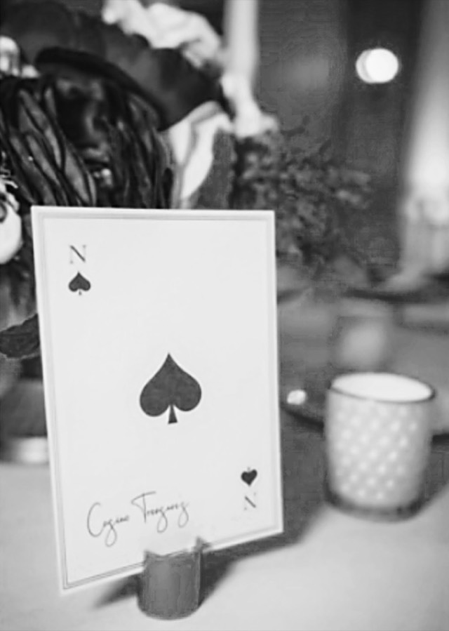 Destination wedding detail — hand-lettered playing card table number displayed at a candlelit reception — Lux Events by Michelle
